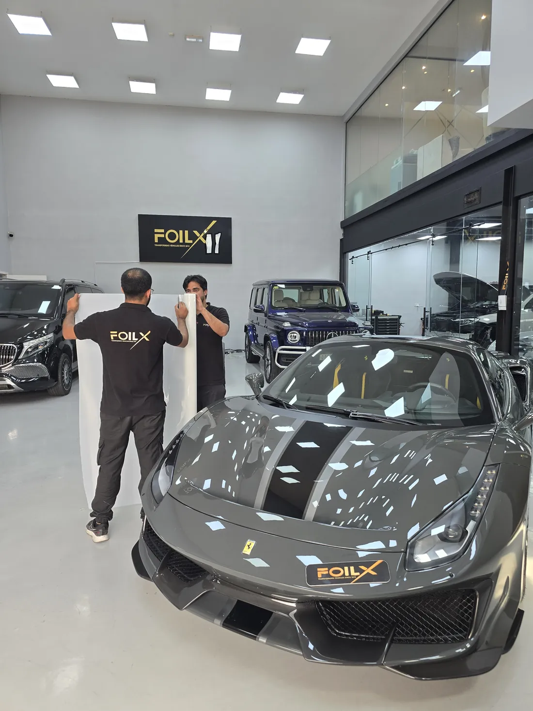 FoilX technicians installing paint protection film on a grey Ferrari